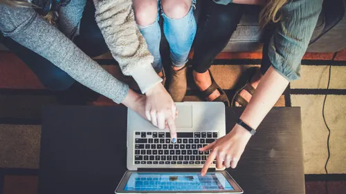 a group of people with one person pointing at a user-centric website on a laptop